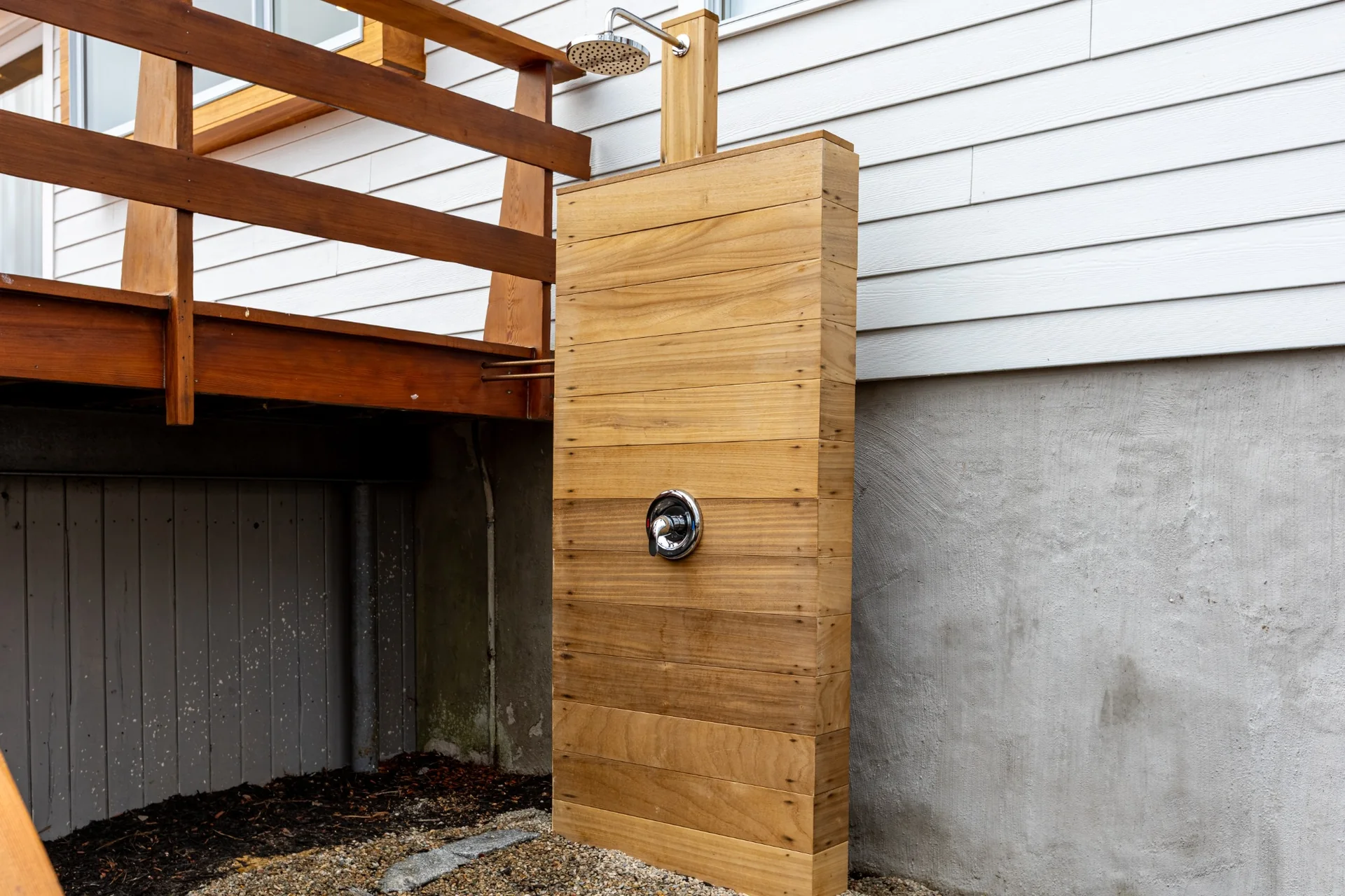 Outdoor shower detail with warm wood cladding, clean hardware, and refined exterior finish work.