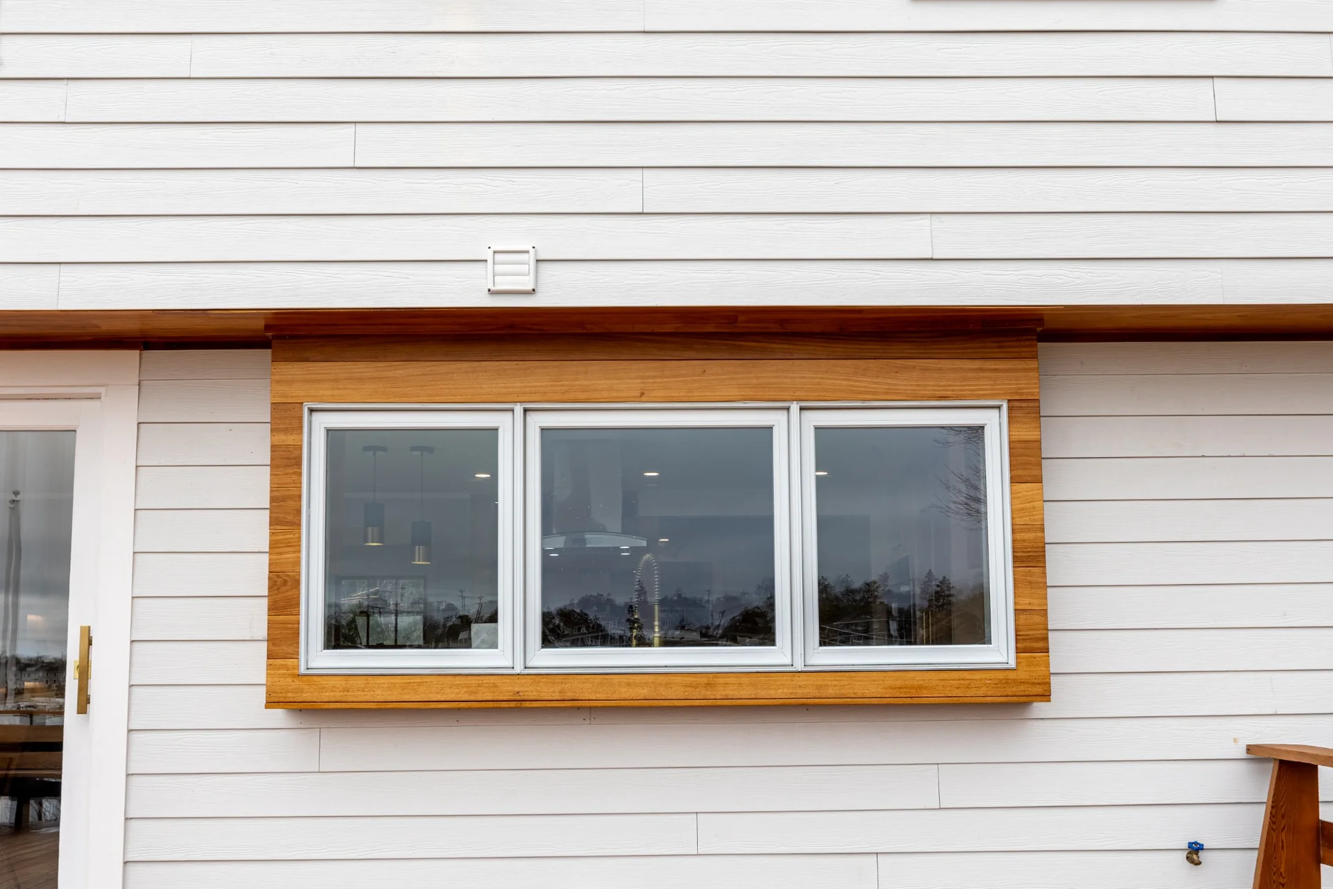 Exterior window trim and warm wood accent detail with clean siding alignment and precise finish work.