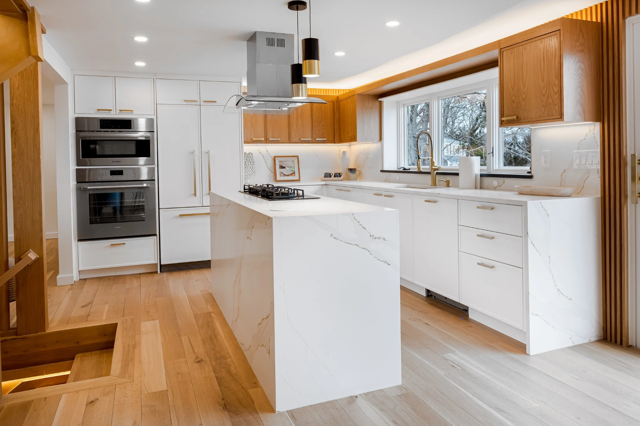 Interior kitchen remodel with custom cabinetry, waterfall island, wood accents, and bright waterfront views.