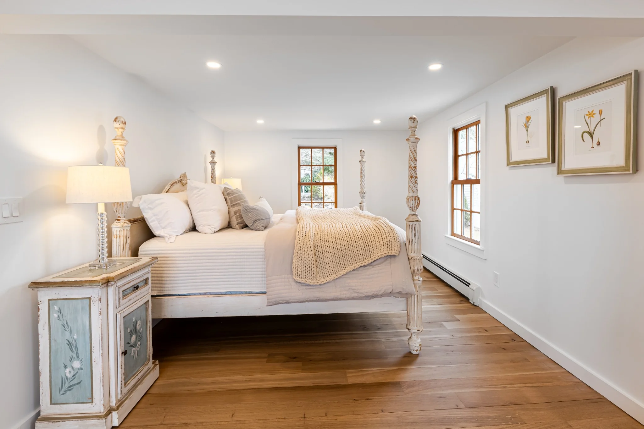 Coastal bedroom with four-poster bed, warm wood tones, soft neutral bedding, and refined interior finish details.
