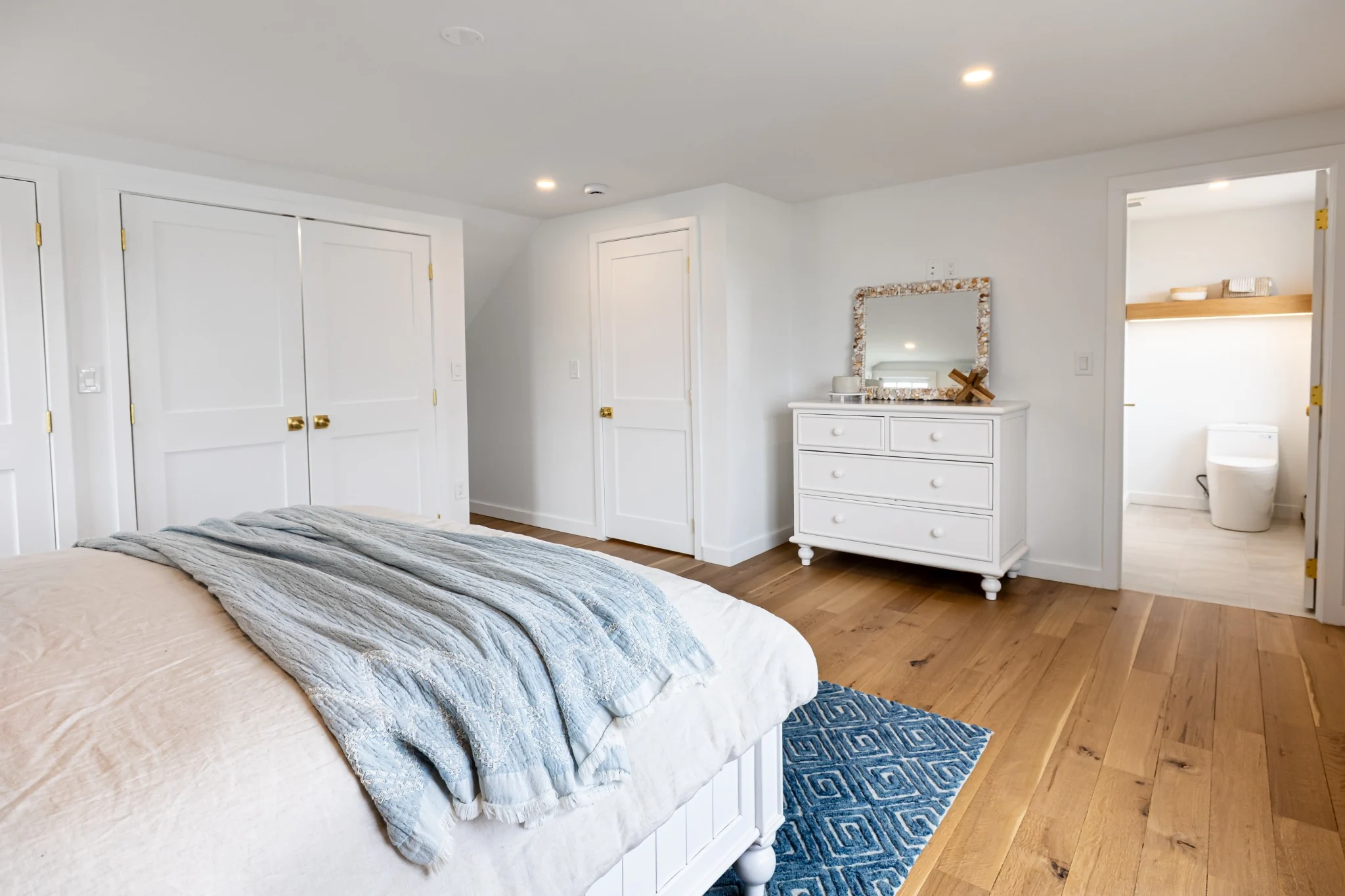 Finished bedroom with ensuite bathroom view, clean flooring, neutral walls, and polished transition details.
