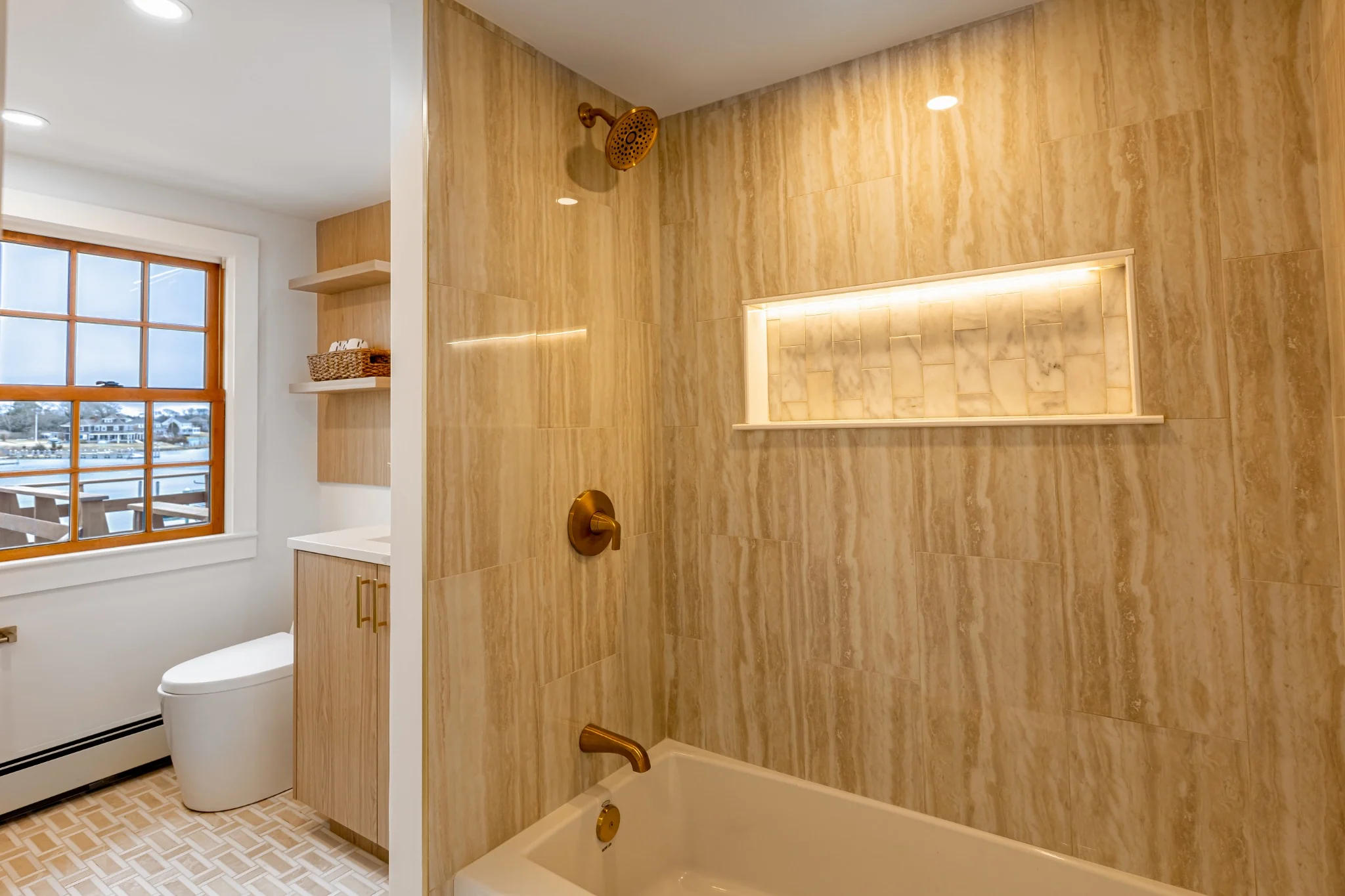 Bathroom remodel with tub shower, gold fixtures, bright tile, warm vanity, and clean finish details.